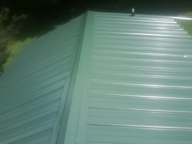 New green metal panels meeting at the ridge of a roof — Flat Roof Repair work by our crew in Taft