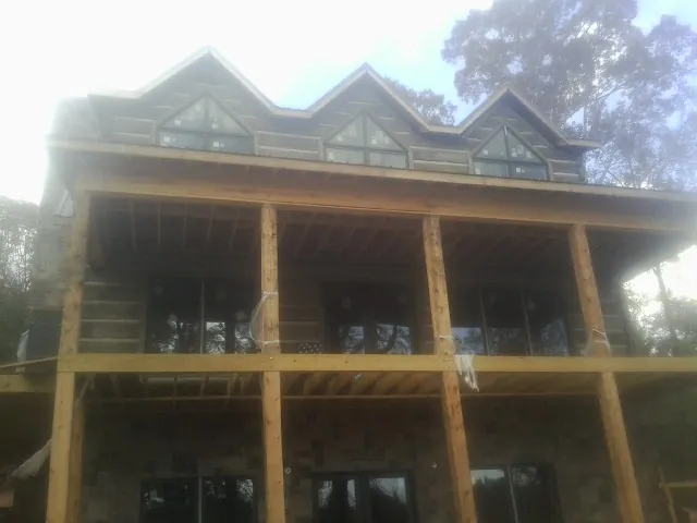 Dormers and porch framing on a large log home under construction — Roof Coating work by our crew in Taft