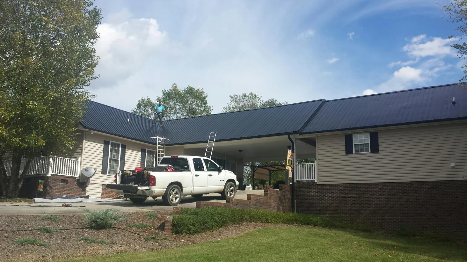 Black metal roof over a home and attached breezeway with ladders set in Taft